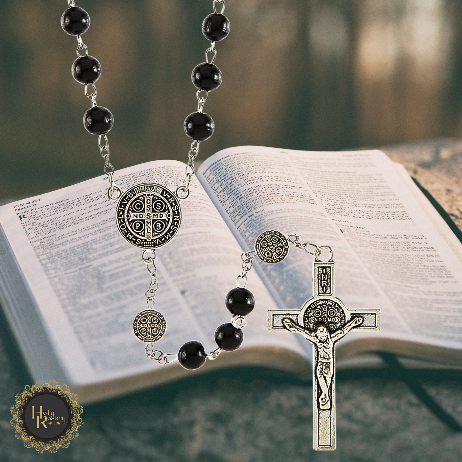 Hanging display of black rosary beads featuring St. Benedict medals and smooth beads